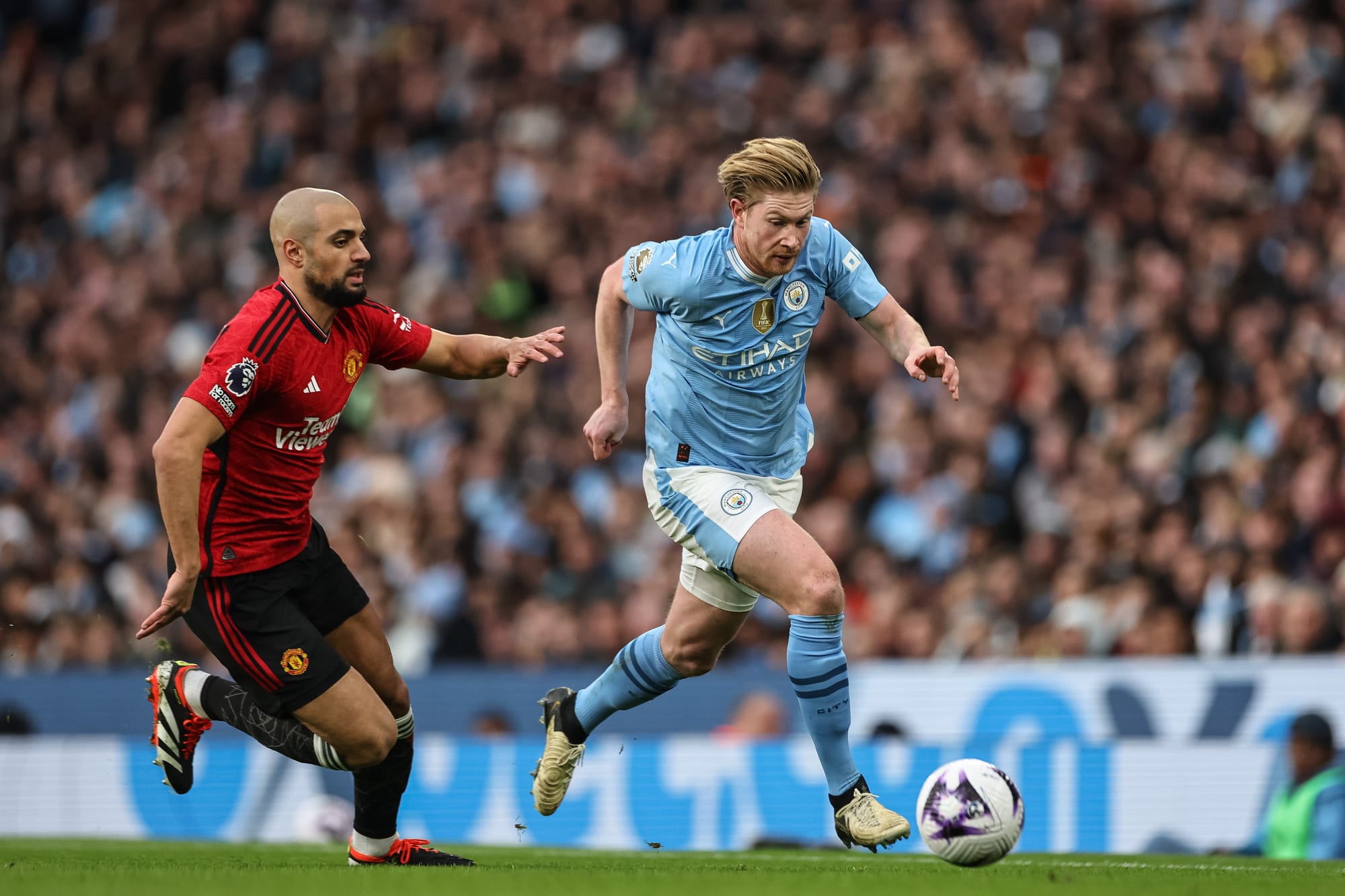 Kevin De Bruyne från Manchester City bryter sig fram med bollen, jagad av Sofyan Amrabat i Manchester United